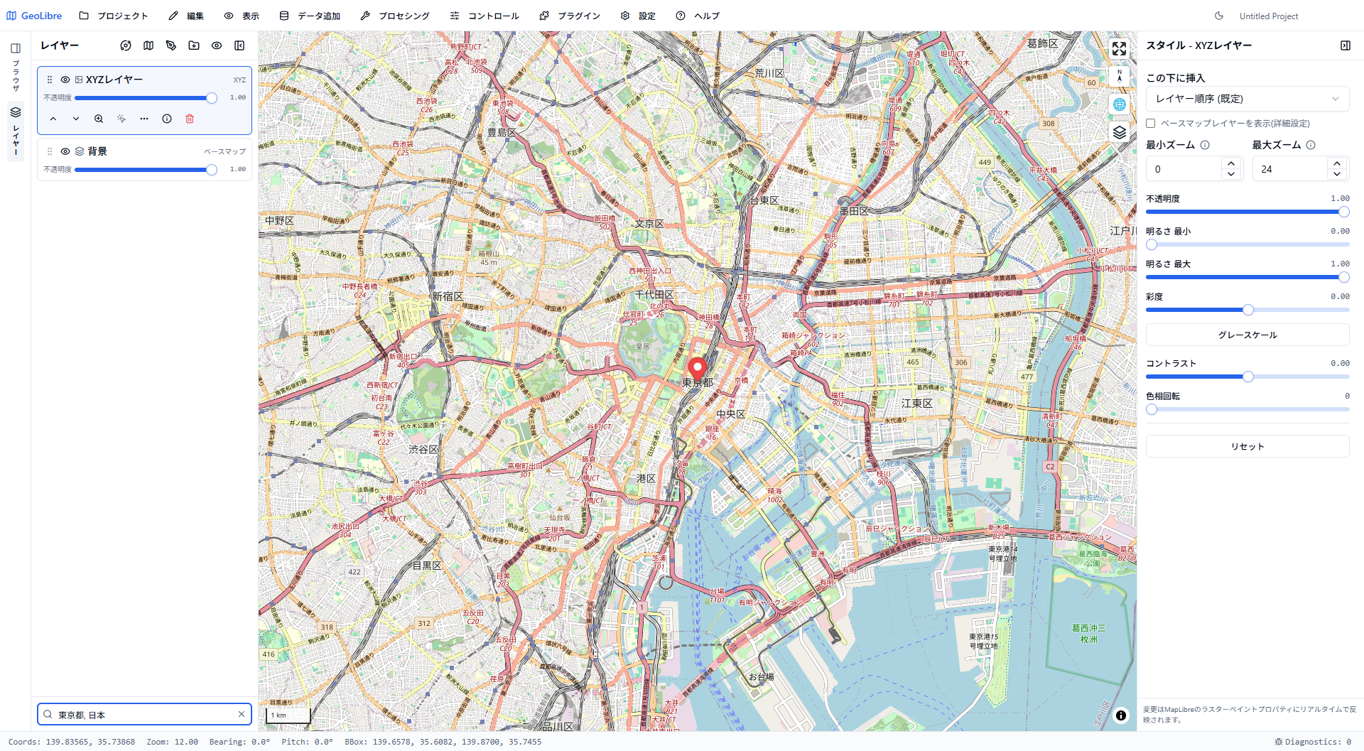 「Tokyo」で検索して東京へ移動した画面。ズーム12でOpenStreetMapのストリートレベルのタイルが表示され、新宿区・千代田区・渋谷区・港区などの区名と東京湾が見える。中央に赤いピン、左下の検索欄には「東京都, 日本」と入っている